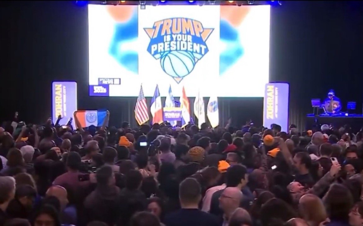 Crowd gathered at a political event featuring a large 