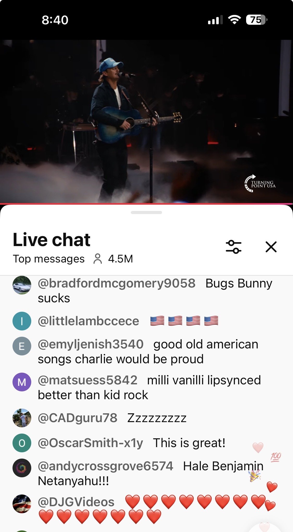 Musician performing on stage with a guitar and microphone, surrounded by a foggy atmosphere during a live event, with a vibrant audience interaction visible in the chat.