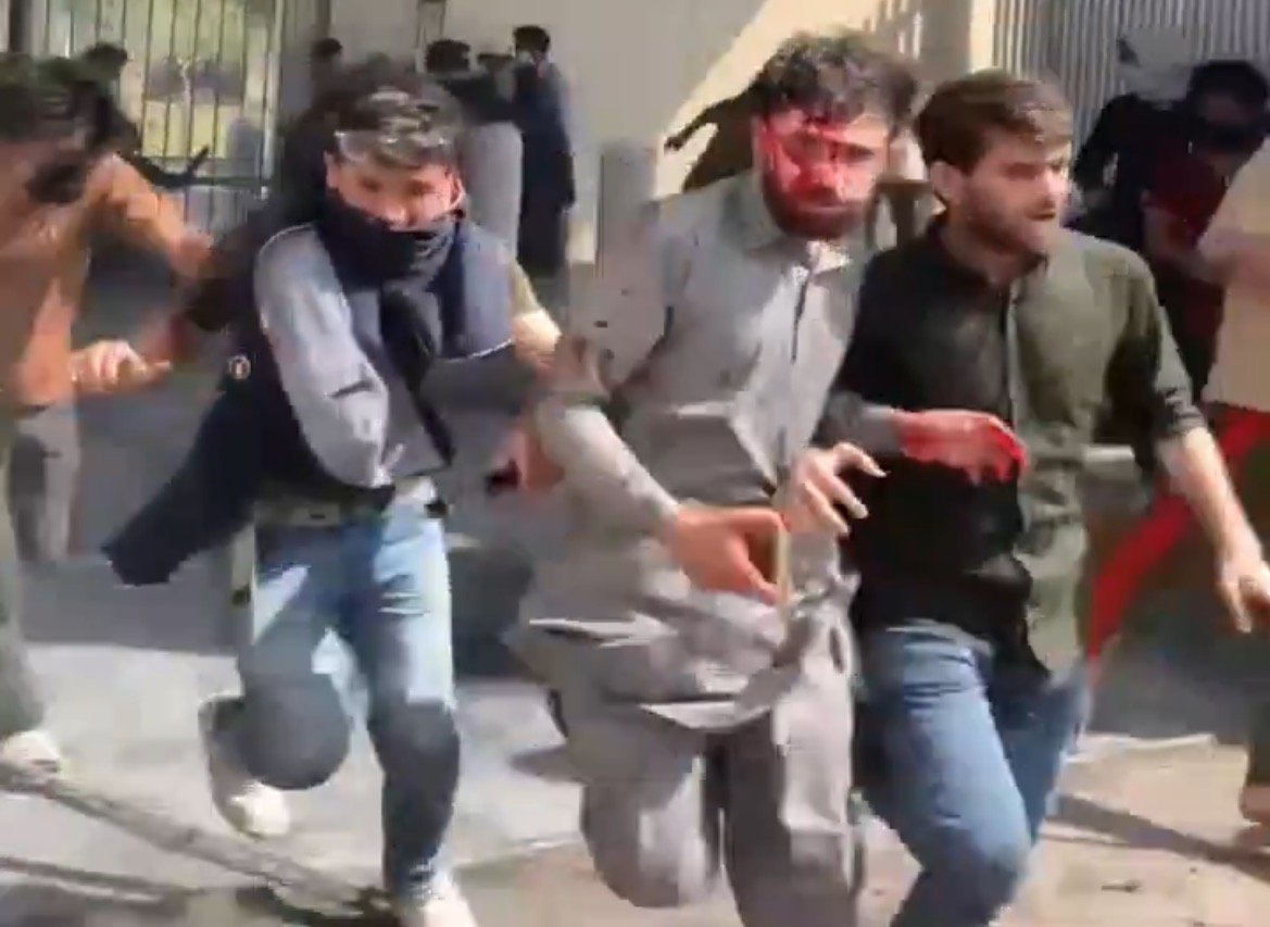 Protesters fleeing from a chaotic scene, with some visibly injured, highlighting the urgency and tension of the situation.