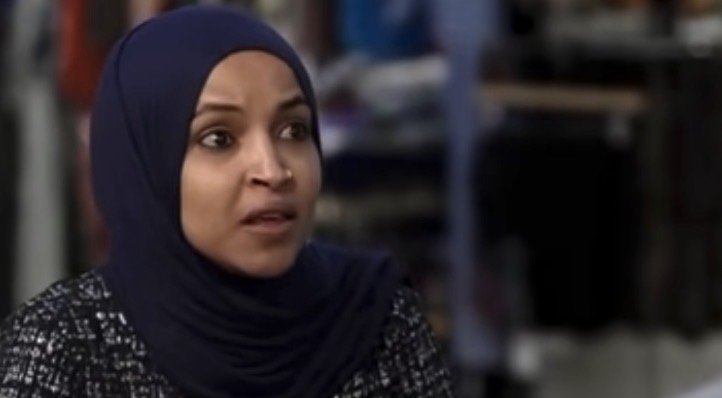 Woman in a hijab expressing concern during an interview, with a blurred retail background.