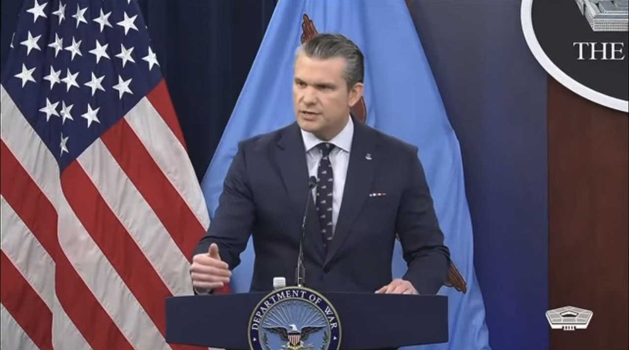 Official delivering a briefing at the Pentagon, with American flags in the background, discussing defense matters and military policies.