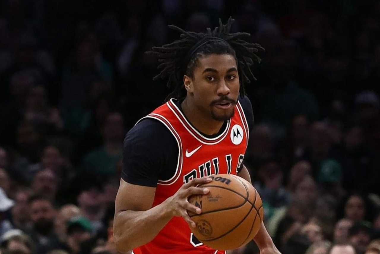 Basketball player dribbling a ball during a game, wearing a Chicago Bulls jersey with a focused expression in an energetic arena setting.