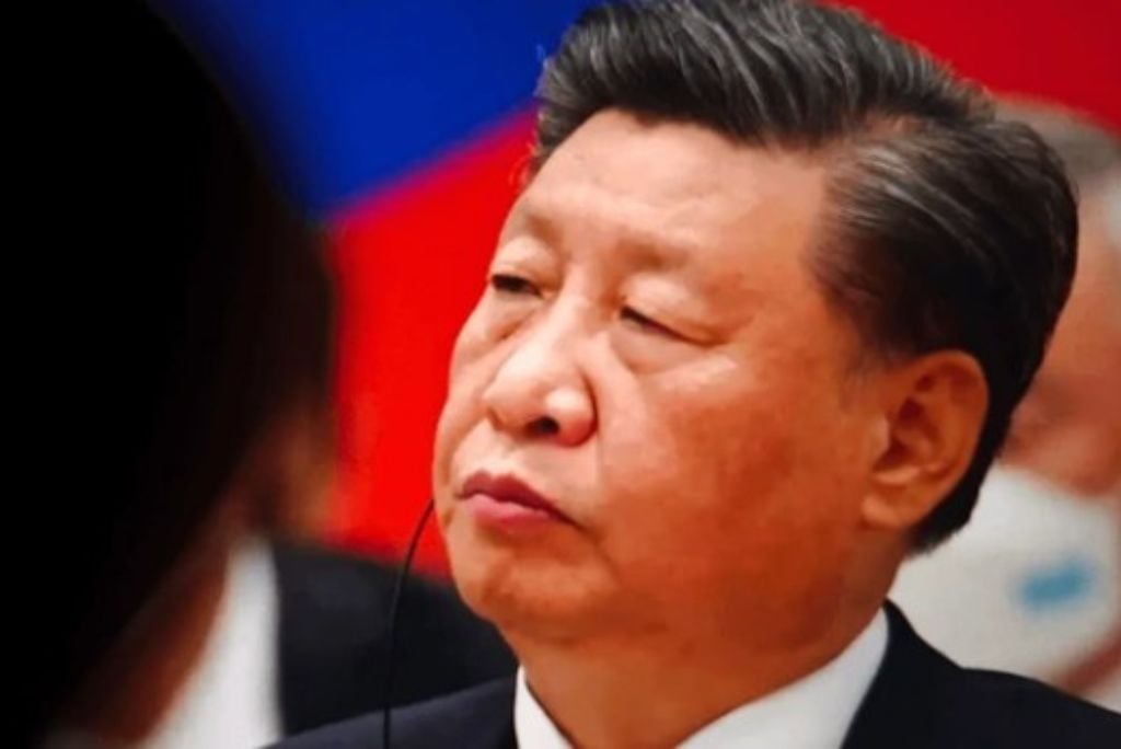 Chinese leader Xi Jinping listens attentively during a diplomatic meeting, showcasing his focused demeanor against a backdrop of national colors.