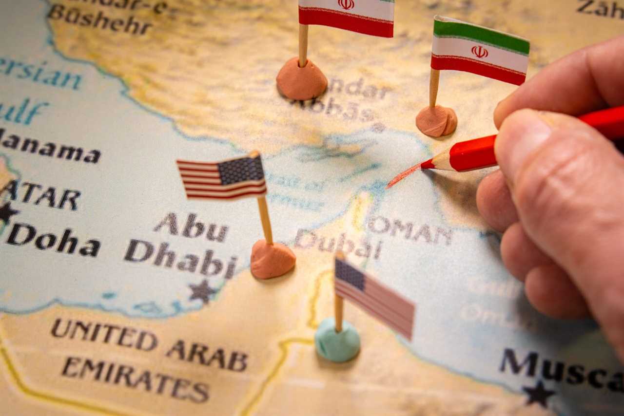 Hand drawing on a map of the Middle East with flags of the USA and Iran, highlighting locations such as Dubai and Abu Dhabi.