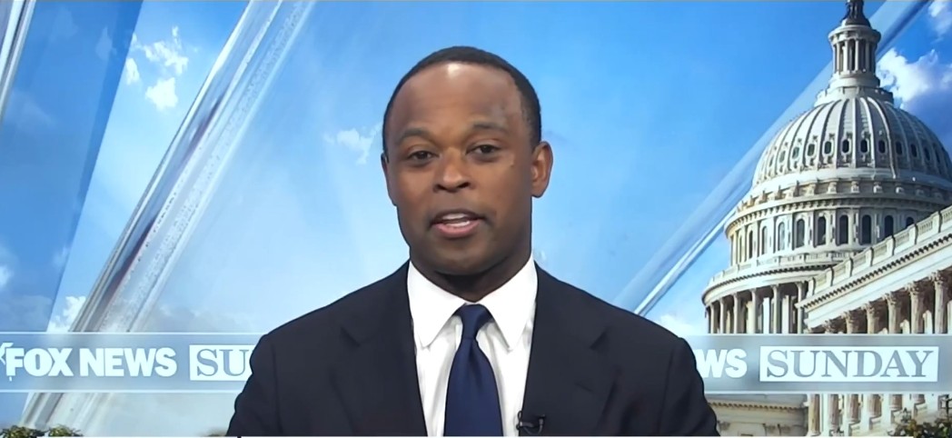 News anchor presenting on Fox News Sunday with the U.S. Capitol in the background.