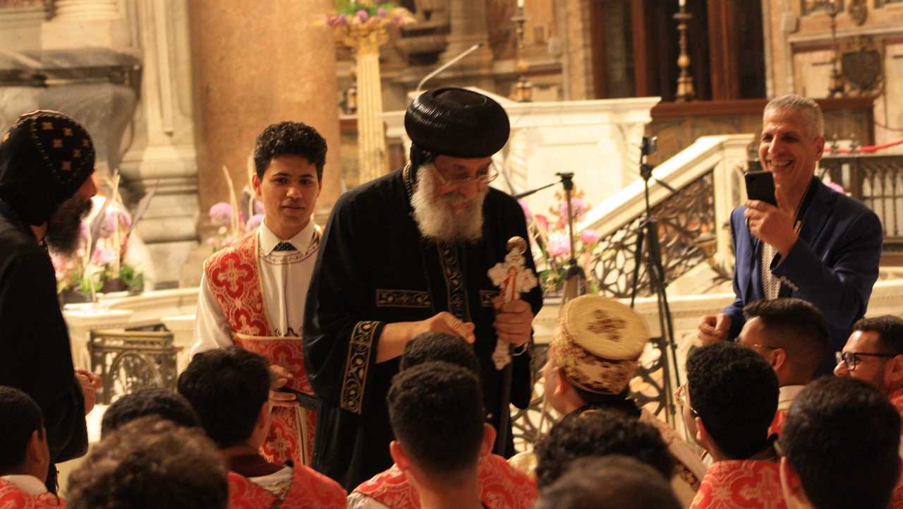 Clerics engage in a joyful moment during a religious ceremony, showcasing traditional attire and a vibrant church setting.