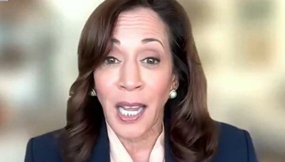 Close-up of a woman speaking passionately during a virtual meeting, wearing a dark blazer and pearl earrings, with a blurred background.